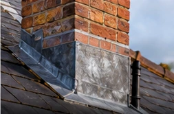 Brick chimney with lead flashing where it meets the roof
