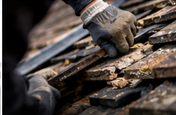 Roofer working on weathered pitched roof tiles